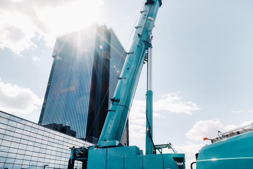 A Boom pump extending its arm to pour concrete on a high-rise building