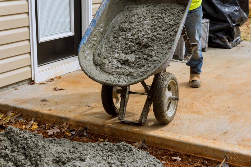 Construction worker using a wheelbarrow to transport concrete